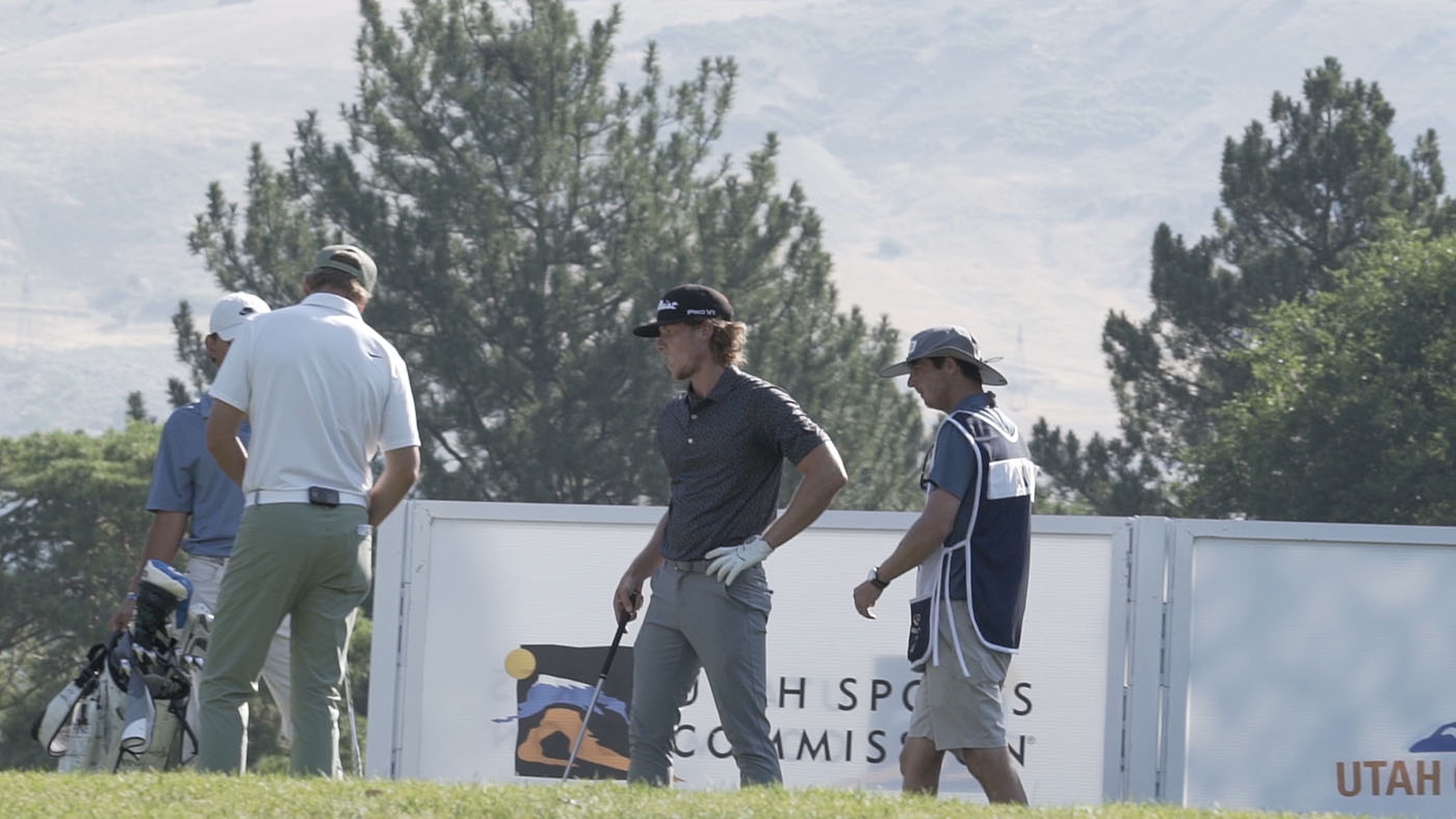 Two golfers walking across a golf course. 