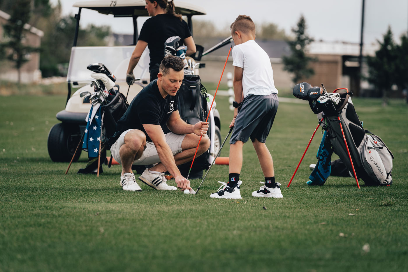 A Tee Box golf instructor helping a younger golfer on our outside course.