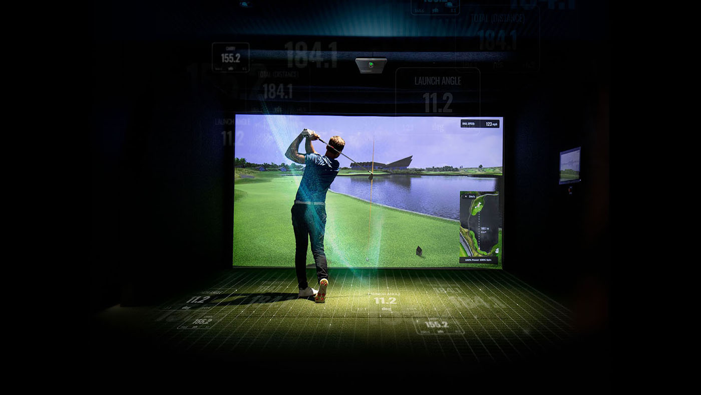 A male Tee Box member practicing his swing on our indoor golf simulator.