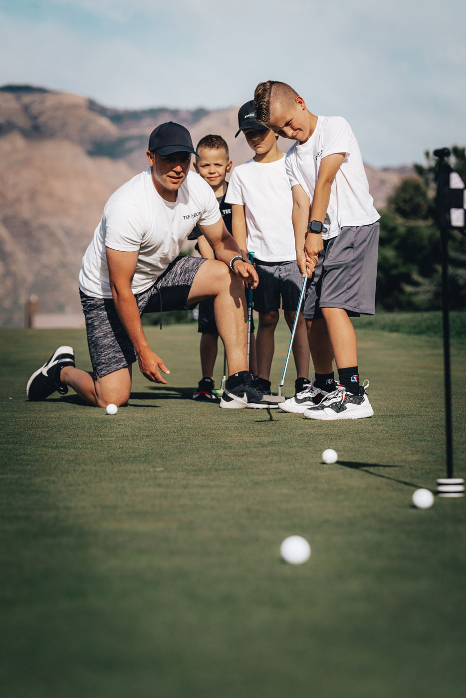 A group of kids playing golf on an outdoor-course at Tee Box.